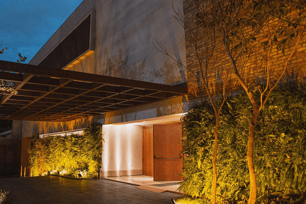 Entrada da Casa Giardini com jardim e iluminação noturna